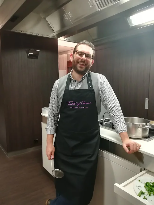 Massimiliano Böhm in cucina, con grembiule e mestolo